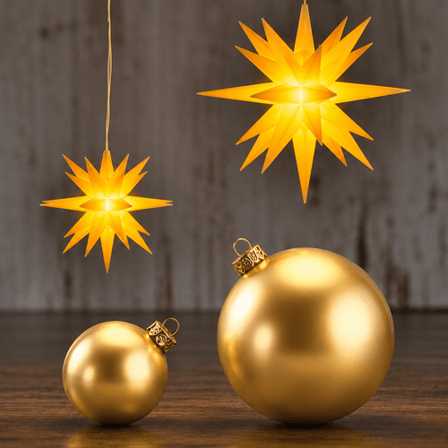 Two Herrnhut Stars on a dark wooden surface against a rustic gray with golden ornaments.