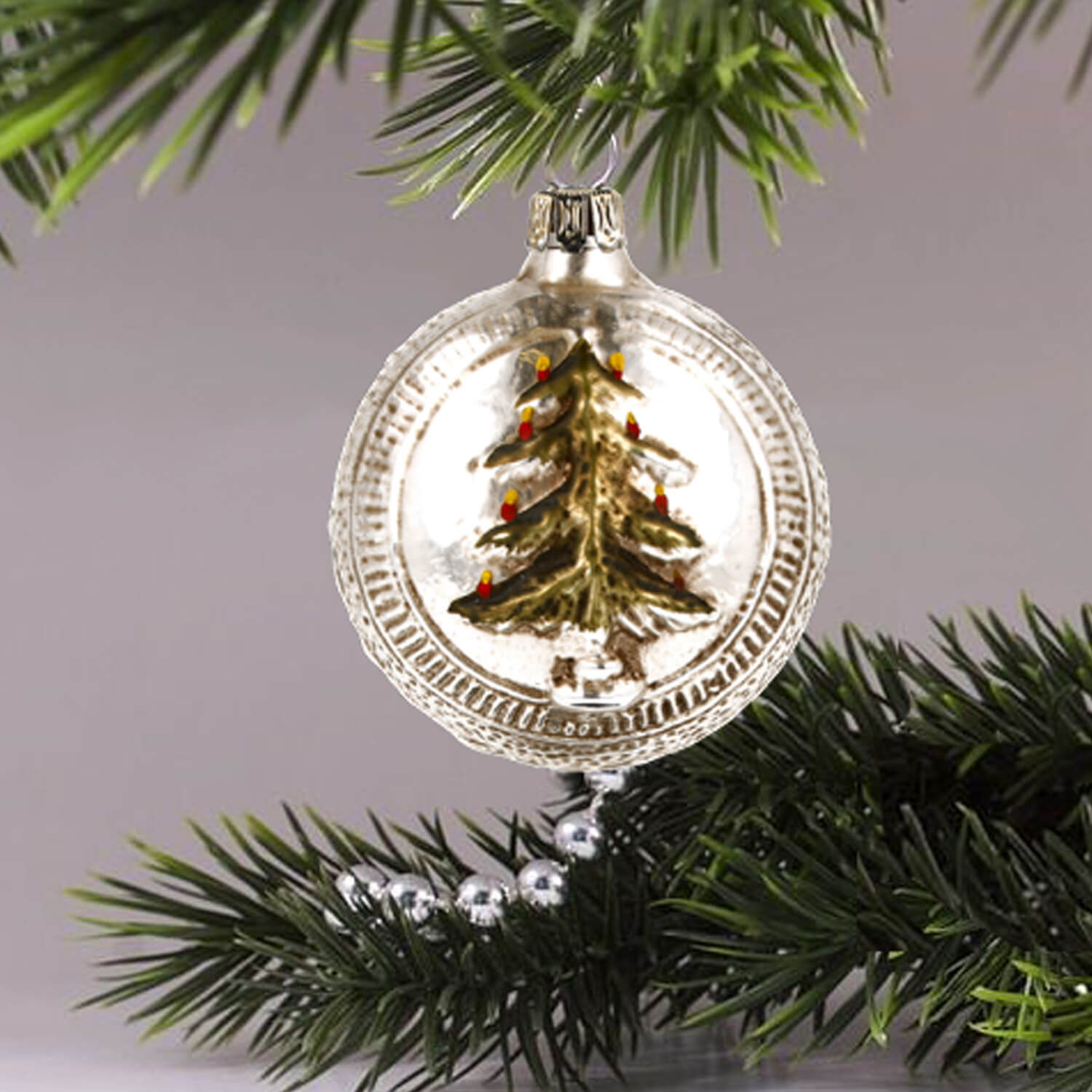 MAROLIN® - Glass ornament "Ball with tree and stars" from the front hanging on a Christmas tree