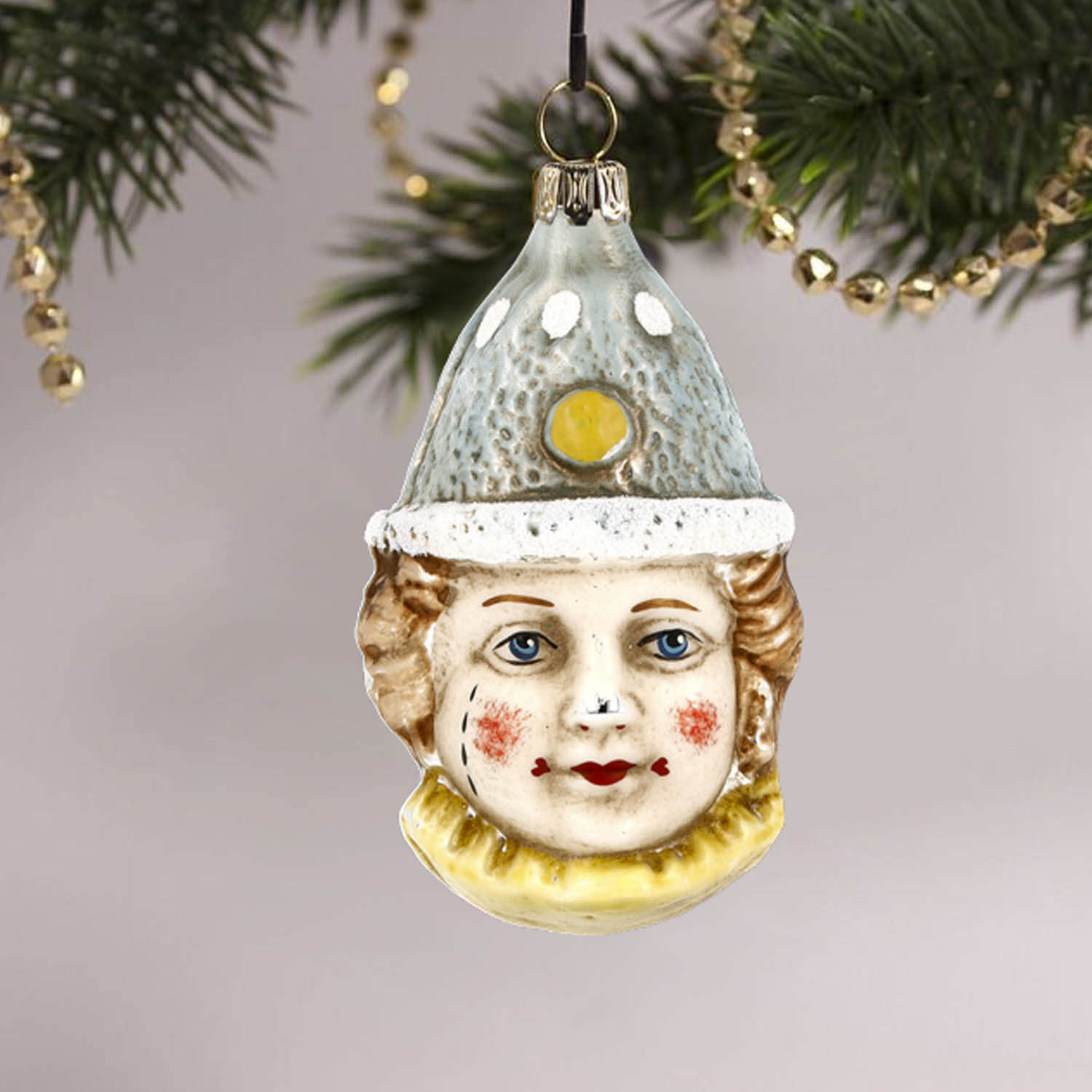 MAROLIN® - Glass ornament "Clown with blue hat" hanging on decorated Christmas tree