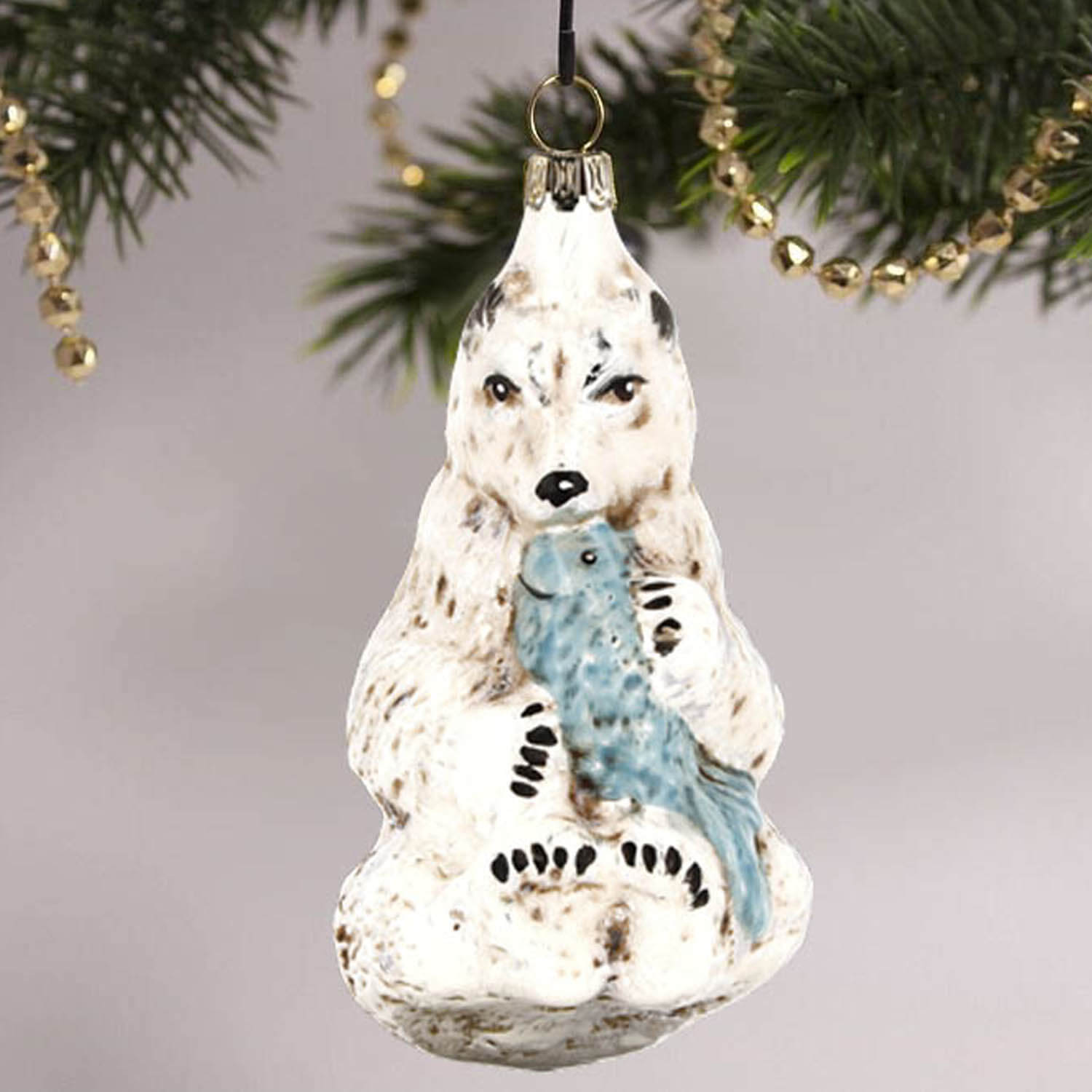 MAROLIN® - Glass ornament "Polar bear with fish" hanging on a golden decorated Christmas tree.