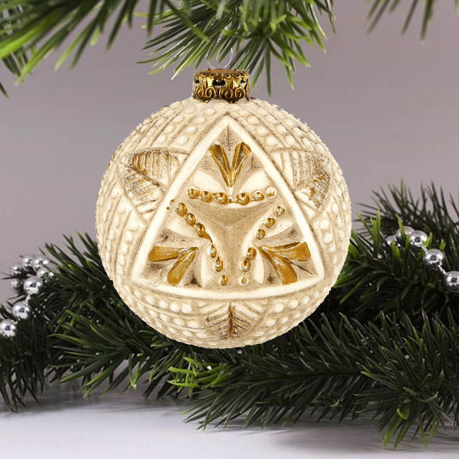 Elegant paper-mâché ornament featuring a white and gold triangle design hanging on Christmas tree.