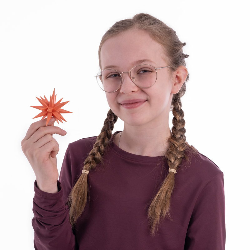 Original Herrnhut plastic MINISTAR, APRICOT (Special Edition 2026) in childs hand