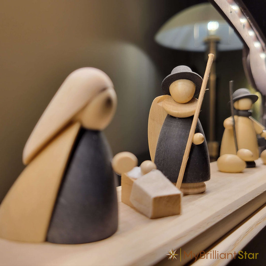 Wooden nativity scene with arch and lit candles on a dark background