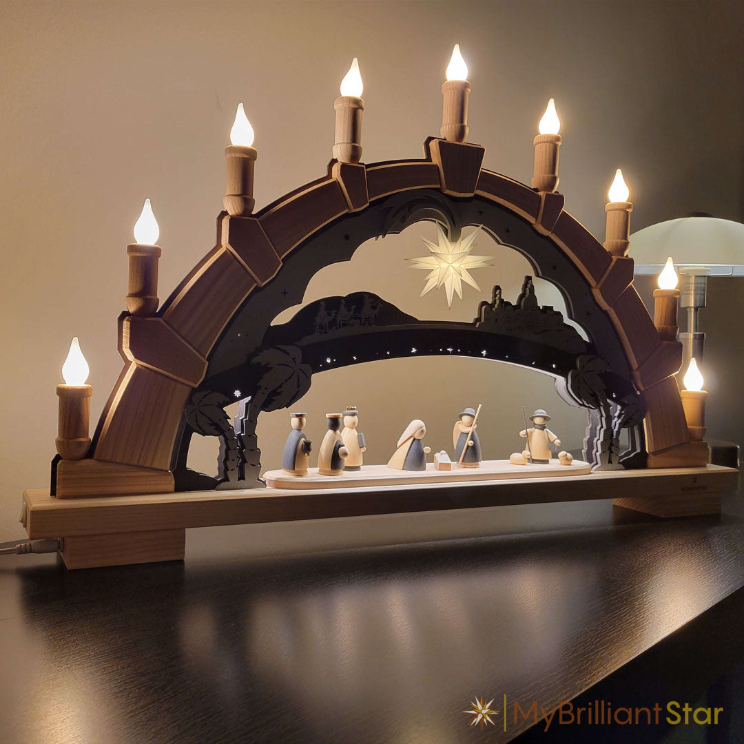 Wooden nativity scene with arch and lit candles on a dark background
