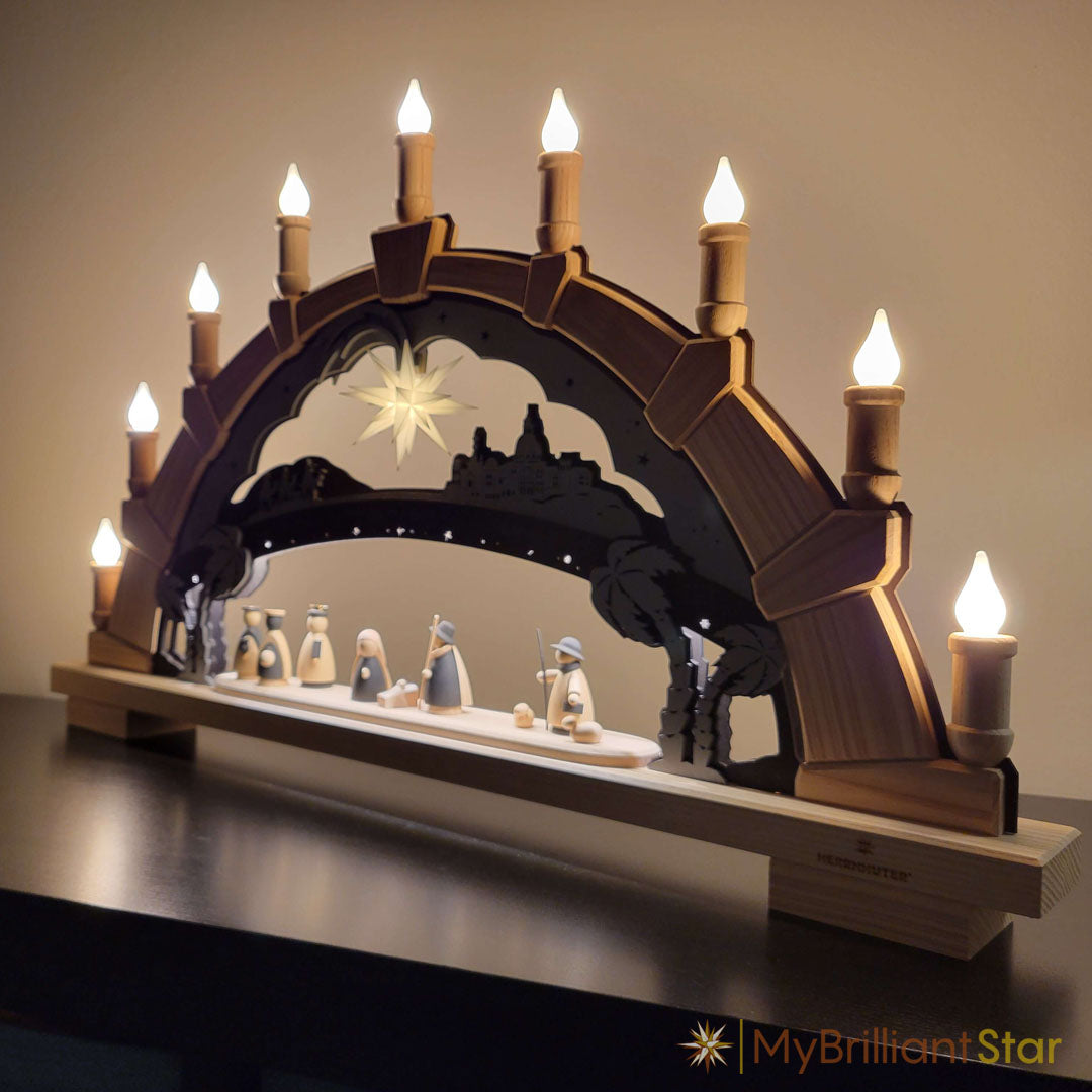 Wooden nativity scene with arch and candles on a dark surface.