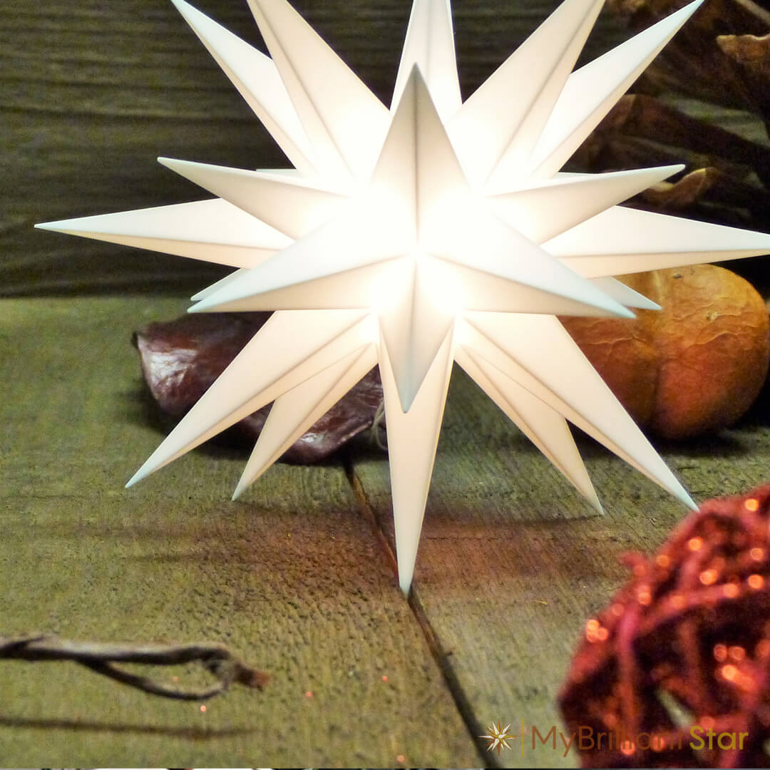 White Herrnhut plastic star white laying on wooden counter