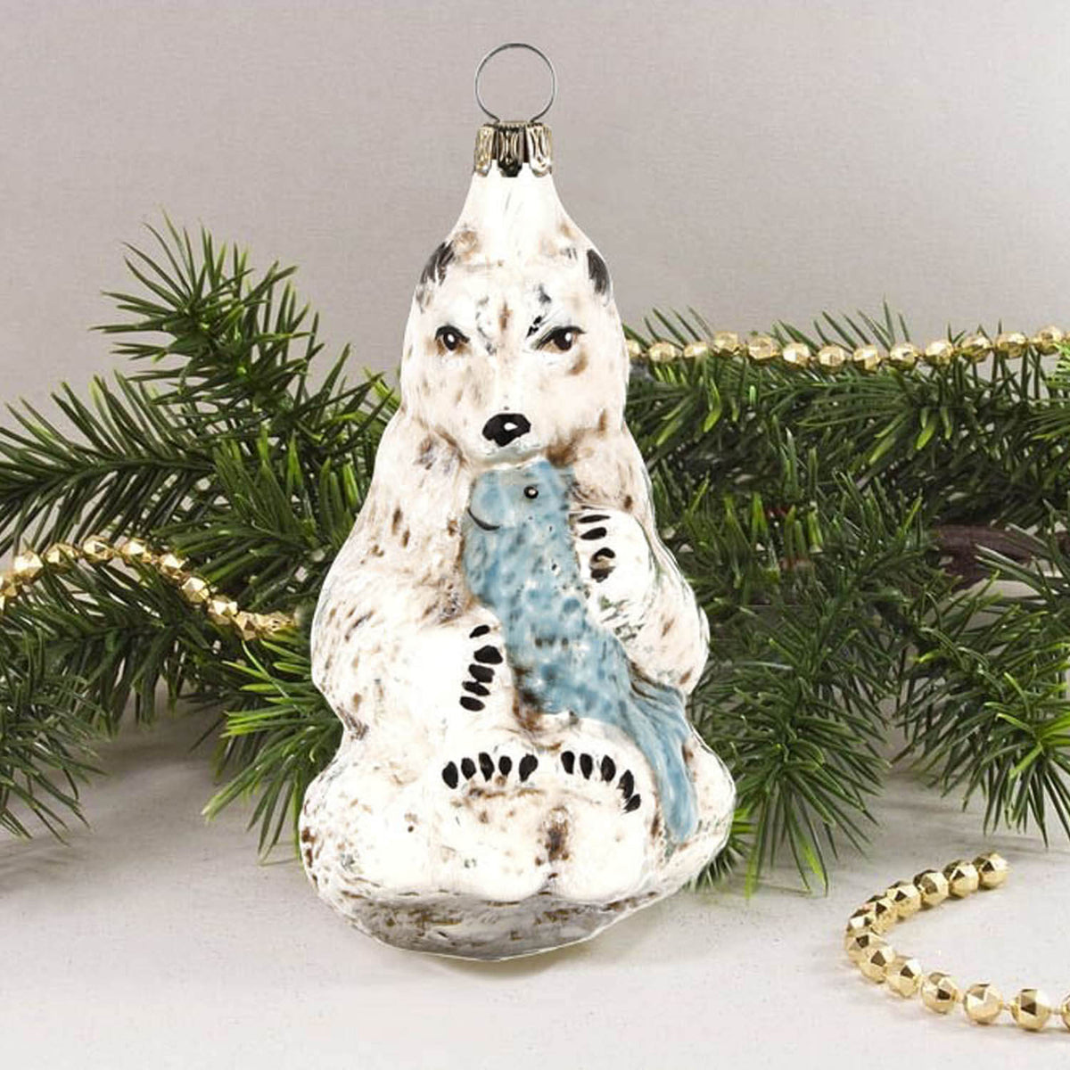 MAROLIN® - Glass ornament &quot;Polar bear with fish&quot; in front of a Christmas tree.