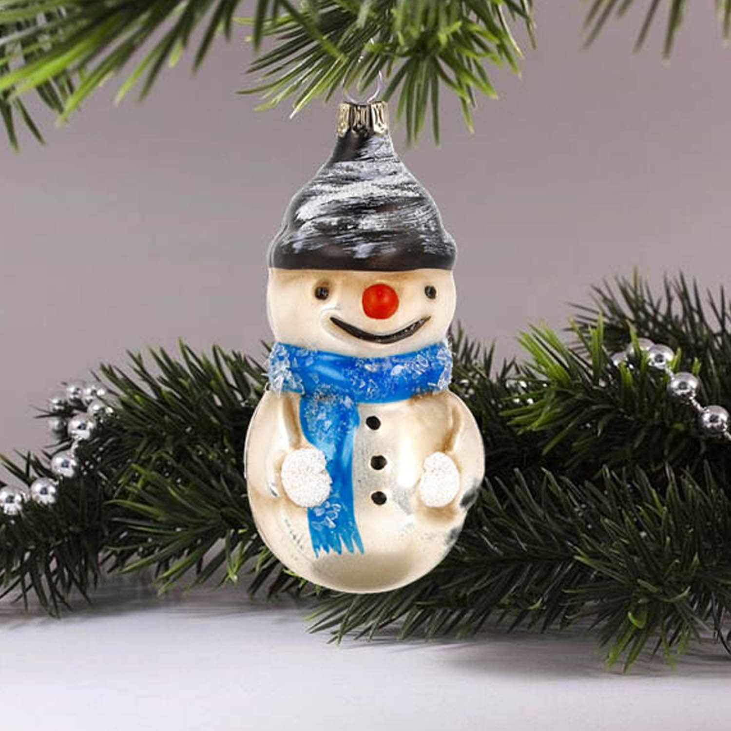 MAROLIN® - Glass ornament "Snowman with scarf and glitter" hanging on a Christmas tree