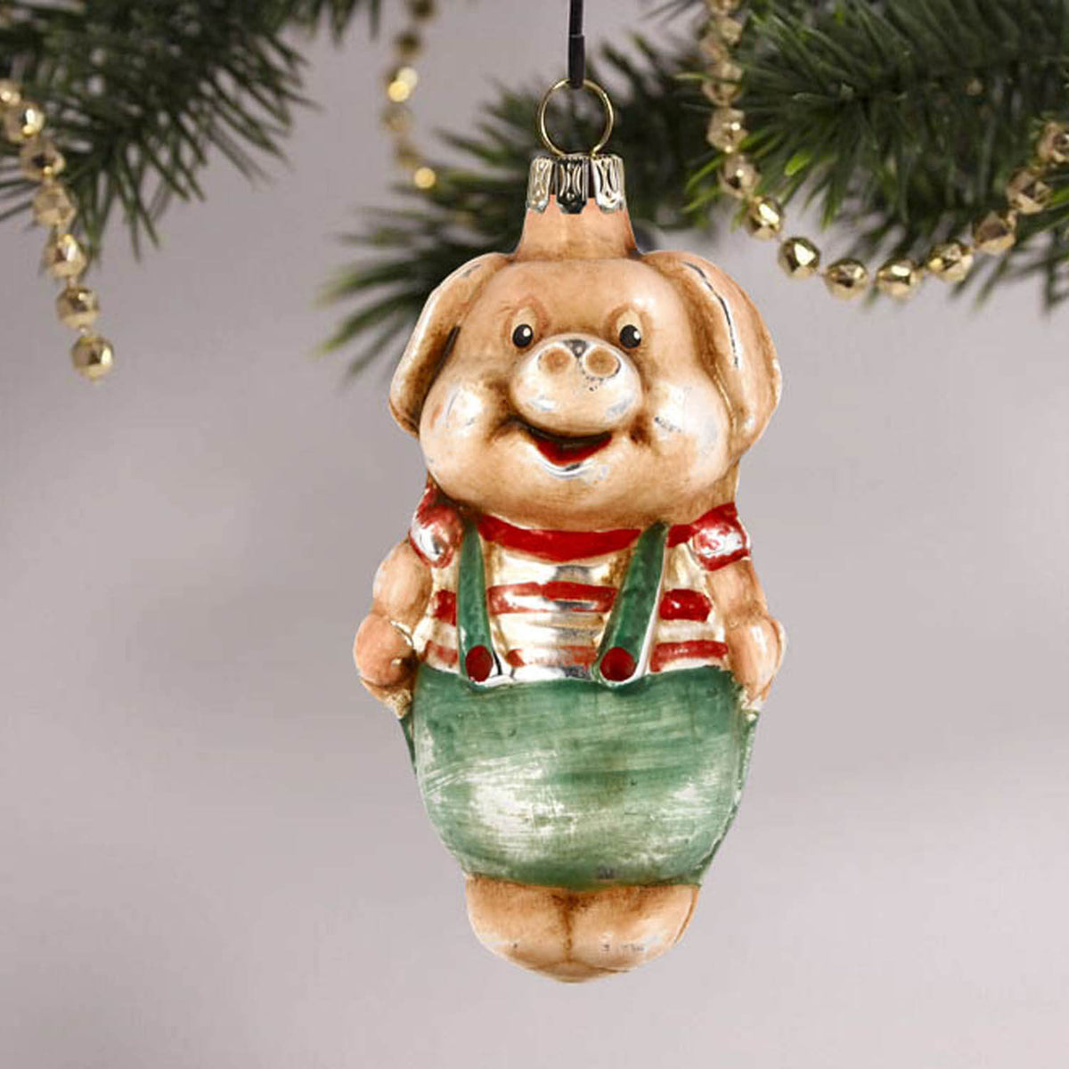 MAROLIN® - Glass ornament &quot;Pig with pants&quot; hanging on a decorated Christmas tree
