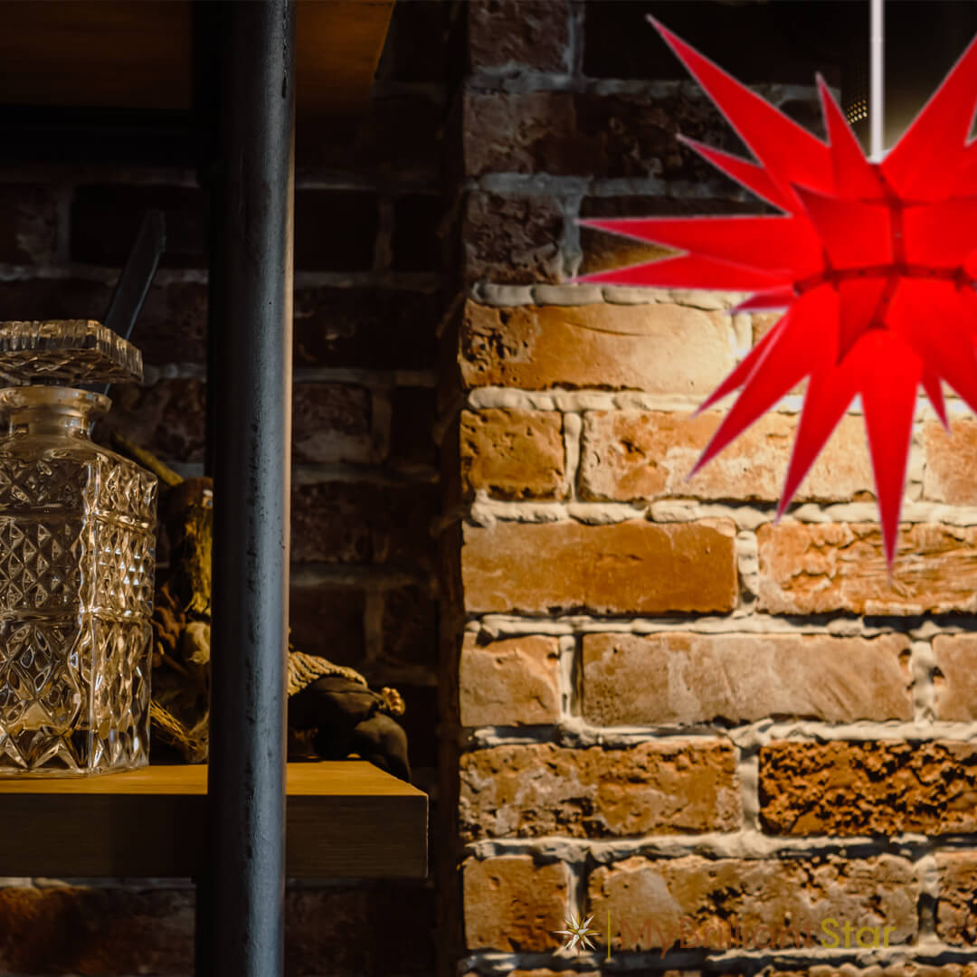 Original Herrnhut paper star, red, ~ 60 cm / 24 inch ø hanging in front of a wall