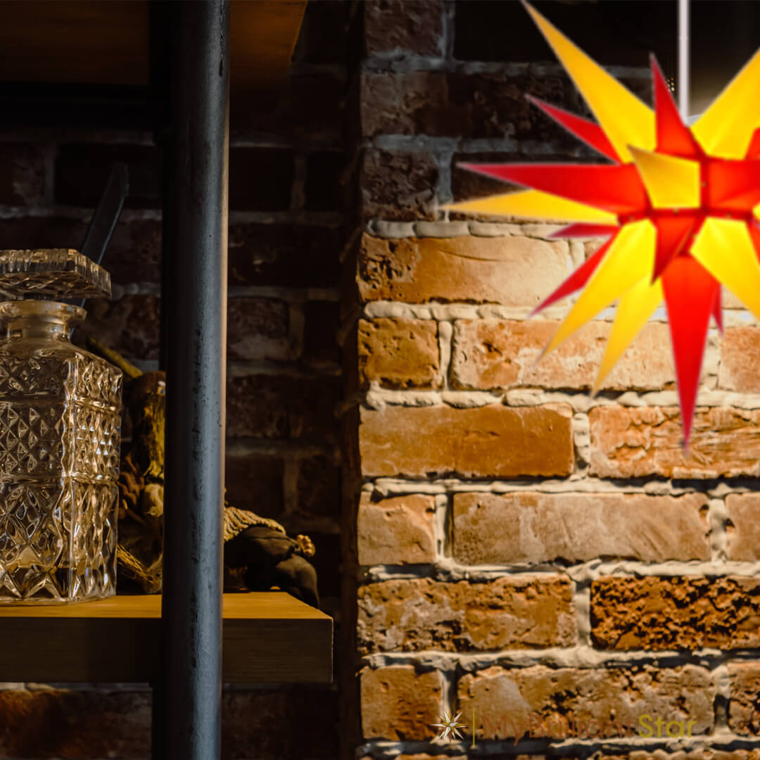 Original Herrnhut paper star, yellow / red, ~ 60 cm / 24 inch ø in front of a wall 