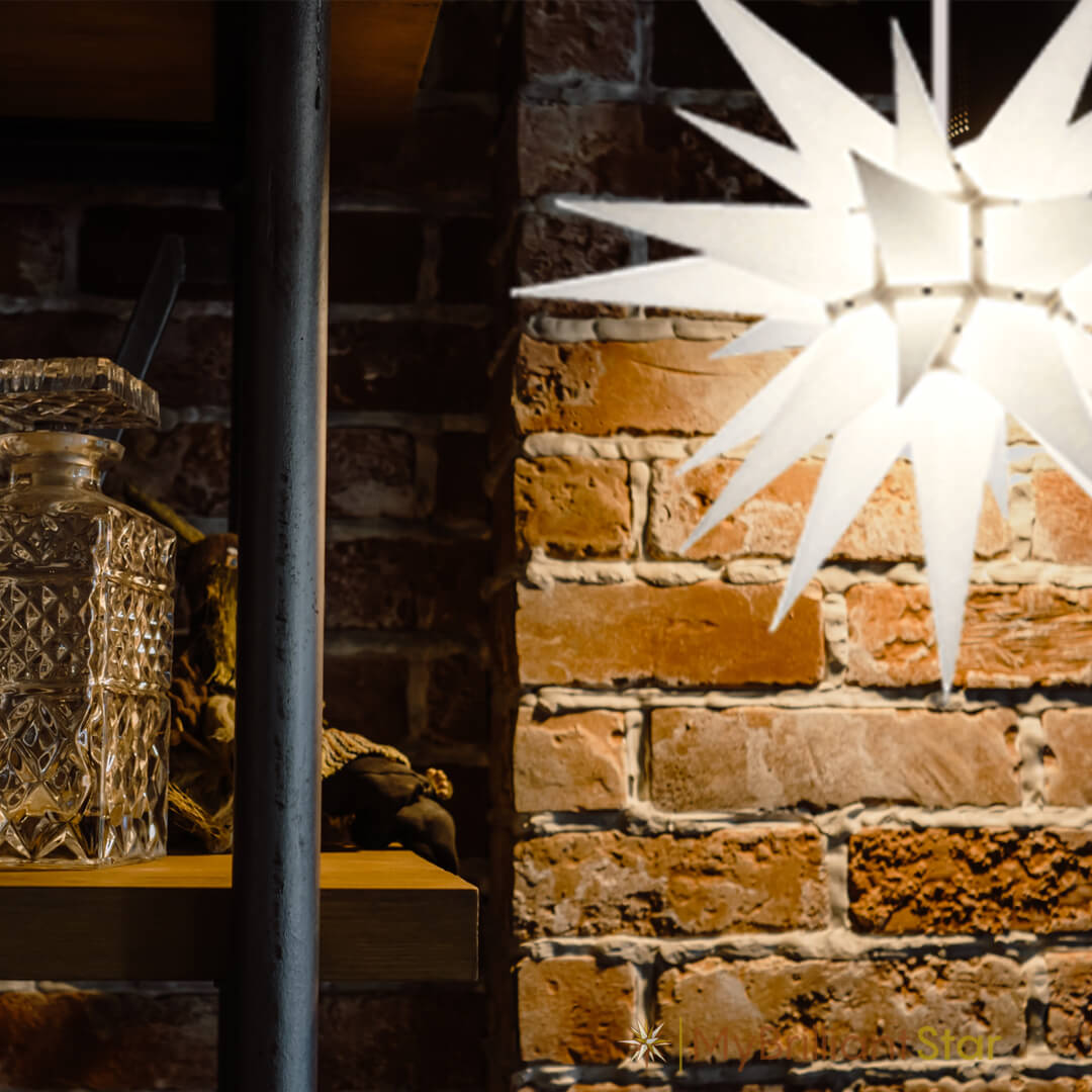 White Herrnhuter star hanging in front of a wall