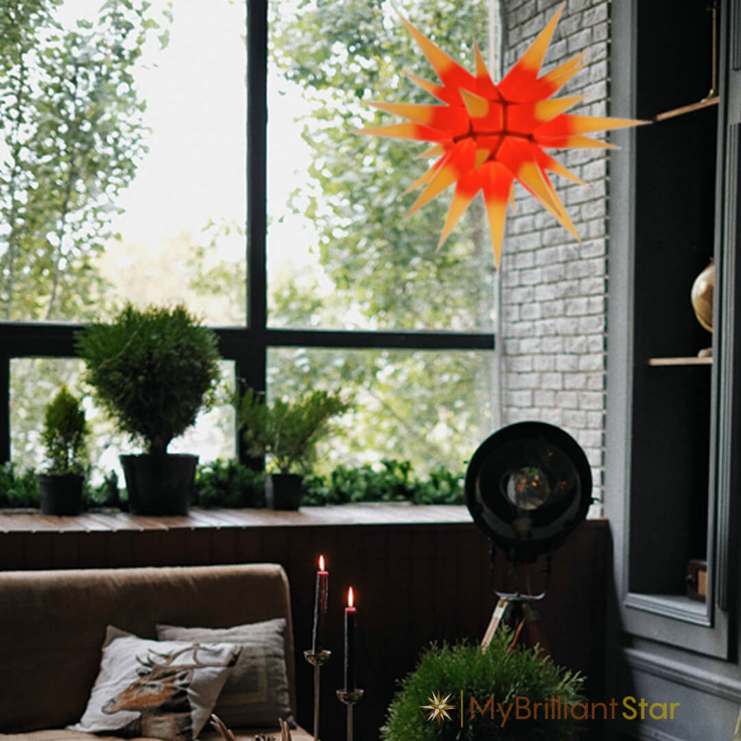 Original Herrnhut paper star, yellow / red center, ~ 70 cm / 27 inch ø hanging in a window above candles