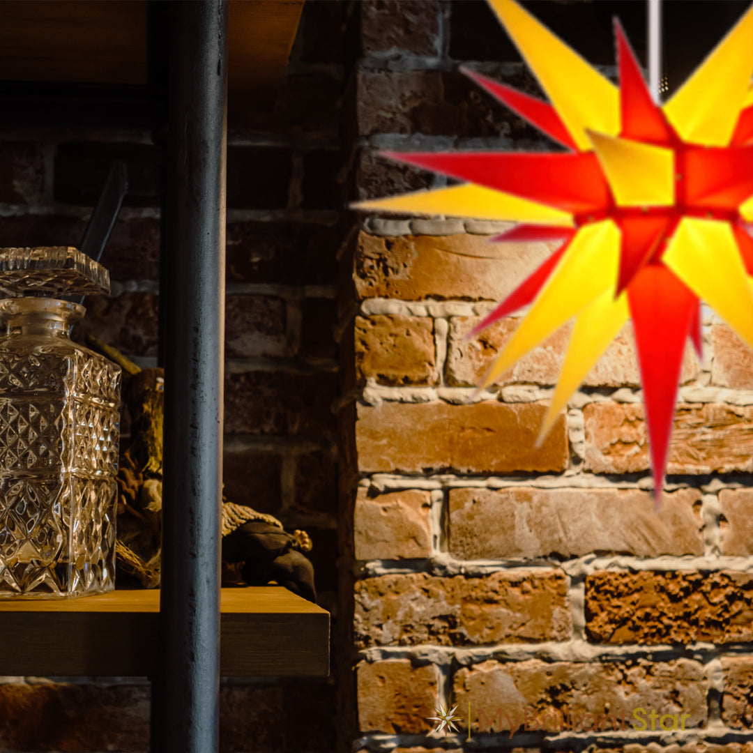 Red and yellow Herrnhuter star hanging in front of a wall